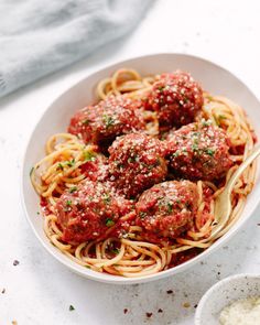 spaghetti with meatballs and tomato sauce in a white bowl