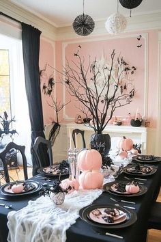 a dining room table decorated with black and white plates, pumpkins and candlesticks