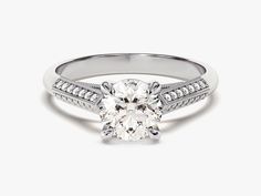 a white gold engagement ring with a round cut diamond in the center and channeled shoulders