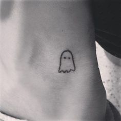 a small ghost tattoo on the side of a woman's foot is shown in black and white