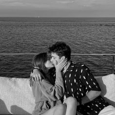 a man and woman sitting on top of a couch next to each other near the ocean