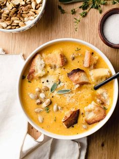 a bowl of soup with toast and nuts on the side