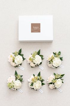 white flowers and greenery are arranged on the table next to a box with labels