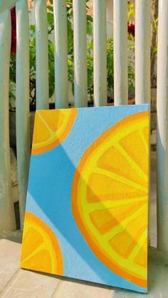 a painting of orange slices on a blue and yellow background with white picket fence behind it