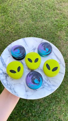 a person holding a plate with four decorated doughnuts on it