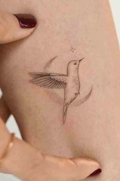 a small hummingbird tattoo on the back of a woman's stomach