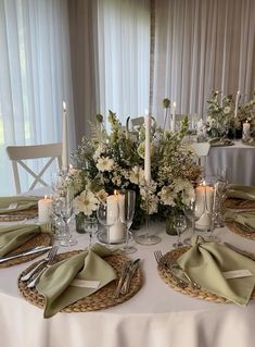 the table is set with silverware and white flowers in centerpieces, along with candles