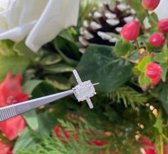 a close up of a pair of scissors with flowers in the background