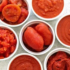 six small white bowls filled with different kinds of sauces and toppings on a table