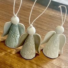 three ceramic angel ornaments sitting on top of a wooden table