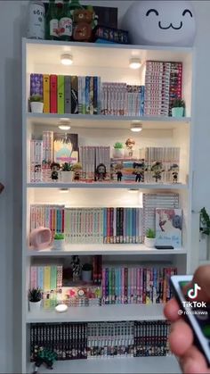 a person holding up a cell phone in front of a book shelf filled with books