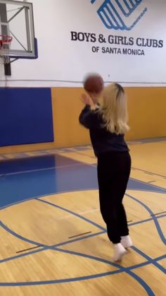 a woman standing on top of a basketball court holding a basketball in her right hand