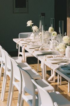 a long table is set with white flowers and place settings for an elegant dinner party