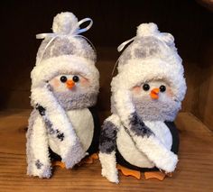 two stuffed snowmen sitting on top of a wooden shelf