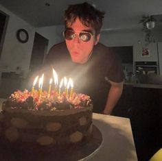 a man in sunglasses blowing out candles on a birthday cake with his eyes wide open