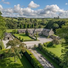 an aerial view of a large house surrounded by lush green trees and grass covered fields