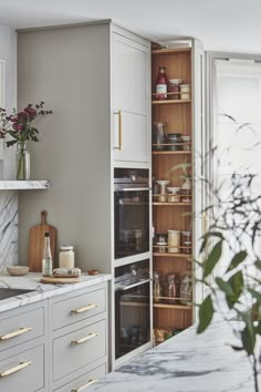 a kitchen with white cabinets and marble counter tops, an oven in the center is surrounded by wooden shelves