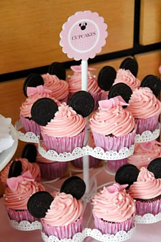 cupcakes with pink frosting and minnie mouse ears are on a cake stand