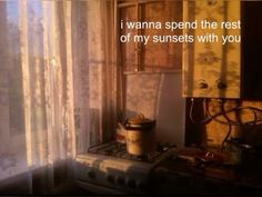 a stove top oven sitting next to a window with curtains on the outside and an old fashioned cooking pot in front of it