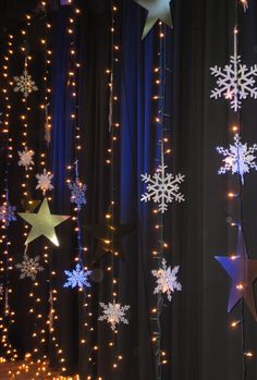 christmas lights and snowflakes are hanging from the ceiling in front of black curtains