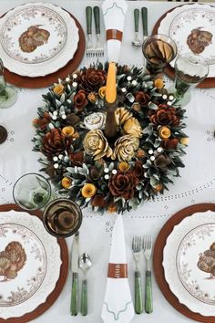 the table is set for thanksgiving dinner with plates, silverware and turkey napkins