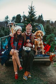 a man and woman sitting in the back of a truck with a dog