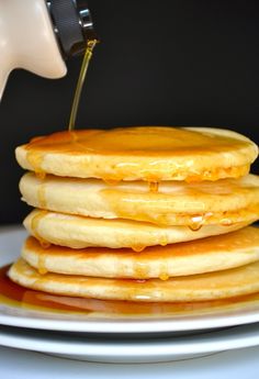 a stack of pancakes with syrup being poured on top