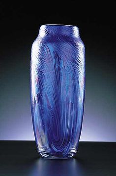 a blue glass vase sitting on top of a black table next to a dark background