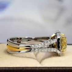 a yellow and white diamond ring sitting on top of a box