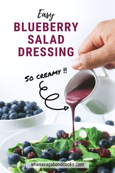 blueberry salad dressing being drizzled onto a plate with berries and spinach