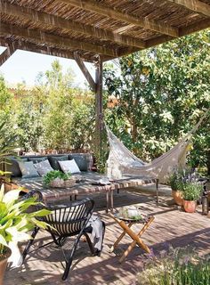 a patio with hammock, chairs and potted plants