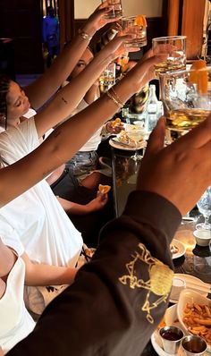 a group of people sitting at a long table with food and drinks in their hands