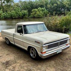 an old pick up truck is parked by the water