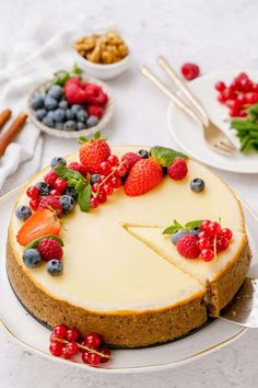 a cheesecake topped with berries and blueberries on a plate next to other desserts