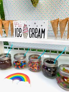 an ice cream stand with rainbows and sprinkles in jars on the table