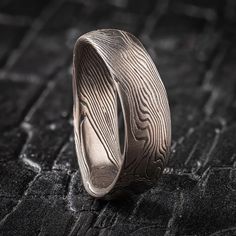 "* Price may vary depending on ring size, please inquire with us directly with your needed size for accurate pricing! This unique and quirky Mokume Gane ring is shown in the Twist pattern and Ash Palette, with a low dome profile, and an etched and oxidized finish. The band is made in a specialized undulating shape. The Ash palette features a combination of Palladium, and Sterling Silver.  Pattern: Twist Palette: Ash Finish: Etched and Oxidized Profile: Low Dome  Width Shown: 6.5mm Size Shown: 10.5 Price does NOT include stones or setting fees. We care about customer service and would like to hear from you! Please contact us to help create your treasured item, we take your concerns and requests to heart and will work together to create your unique designs SPECIAL PRICING FOR SETS. CONTACT U Unique Engraved Round Ring, Unique Carved Engraved Ring For Promise, Unique Carved Engraved Promise Ring, Adjustable Engraved Ring As A Gift, Unique Carved Adjustable Rings, Modern Etched Ring Jewelry, Modern Etched Rings, Artisan Carved Adjustable Ring, Mokume Gane Ring Wedding