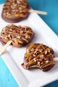 three heart shaped desserts with caramel and pecans on them sitting on a white plate