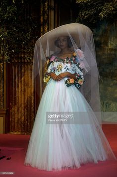 a woman in a wedding dress with a veil over her head, standing on a red carpet