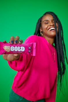 a woman holding up a candy bar in front of a green background with the word god written on it