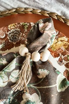 a close up of a plate on a table with a napkin and some wood beads