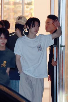 a man in white shirt standing next to a glass door with other people behind him