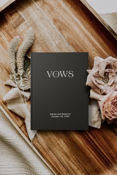 an open book sitting on top of a wooden table next to dried flowers and feathers