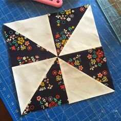 a black and white flowered umbrella sitting on top of a cutting board next to a pink scissors