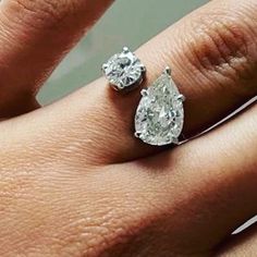 a woman's hand with two diamond engagement rings on top of her ring finger