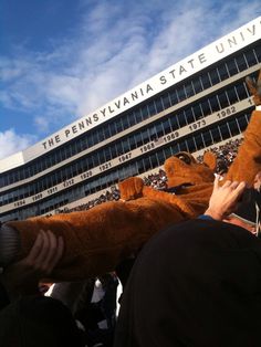 people in front of the pennsylvania state university building with stuffed animals on their heads and hands