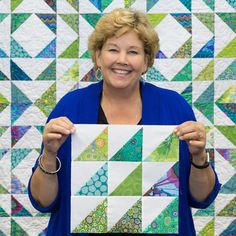 a woman holding up a piece of quilt