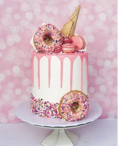 a pink and white cake with sprinkles, donuts, and ice cream