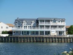 a large white house sitting on the side of a body of water next to a pier