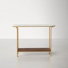 a white table with gold legs and a shelf in the middle on a plain surface