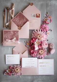 pink and gold wedding stationery with flowers on the bottom right corner, along with matching envelopes